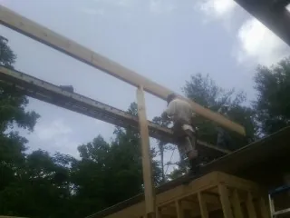 Carpenter setting a ridge beam over a new addition frame — Ice Dam Removal by Roofing Brothers in Tobaccoville