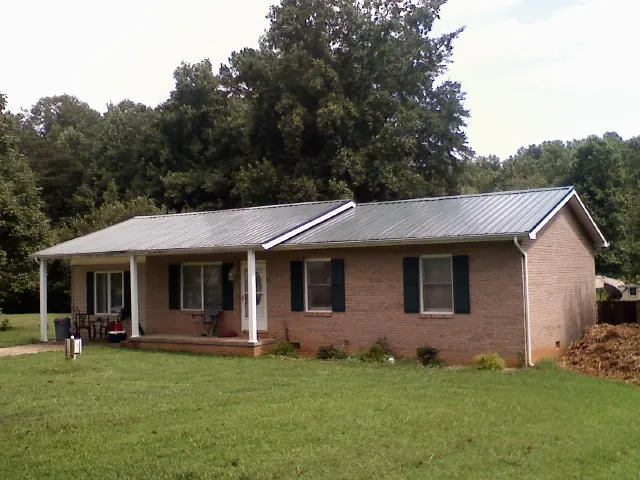Gray metal roof on a brick ranch house with a side carport in Tobaccoville