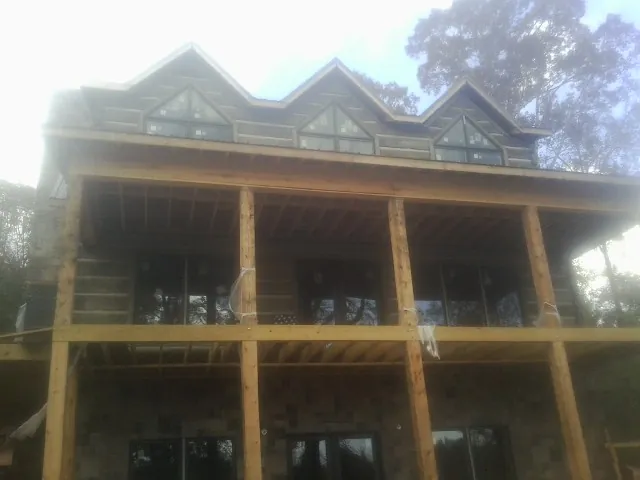 Dormers and porch framing on a large log home under construction — Roof Coating work by our crew in Tobaccoville