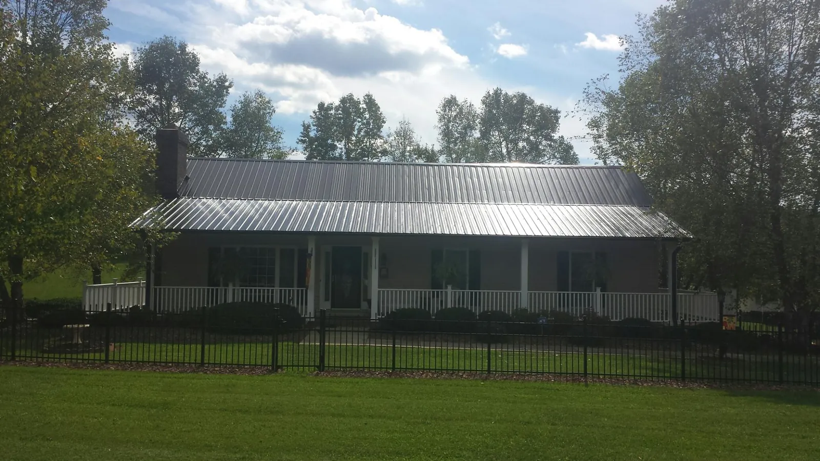 Gray metal roof on a brick ranch with a full width front porch — Gutter Guard Installation work by our crew in Tobaccoville