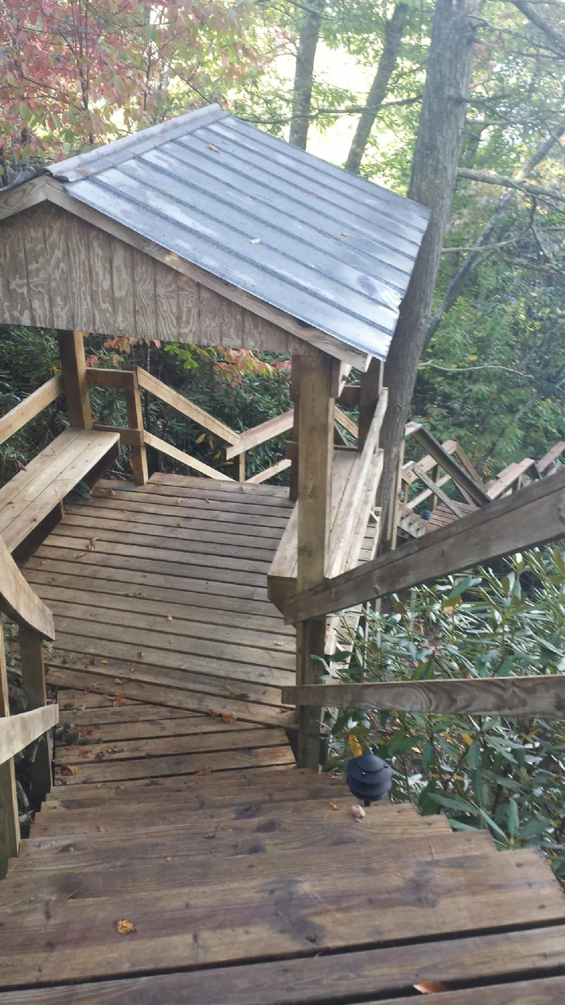 Metal roofed shelter over wooden steps on a wooded walkway — Skylight Repair & Installation work by our crew in Tobaccoville