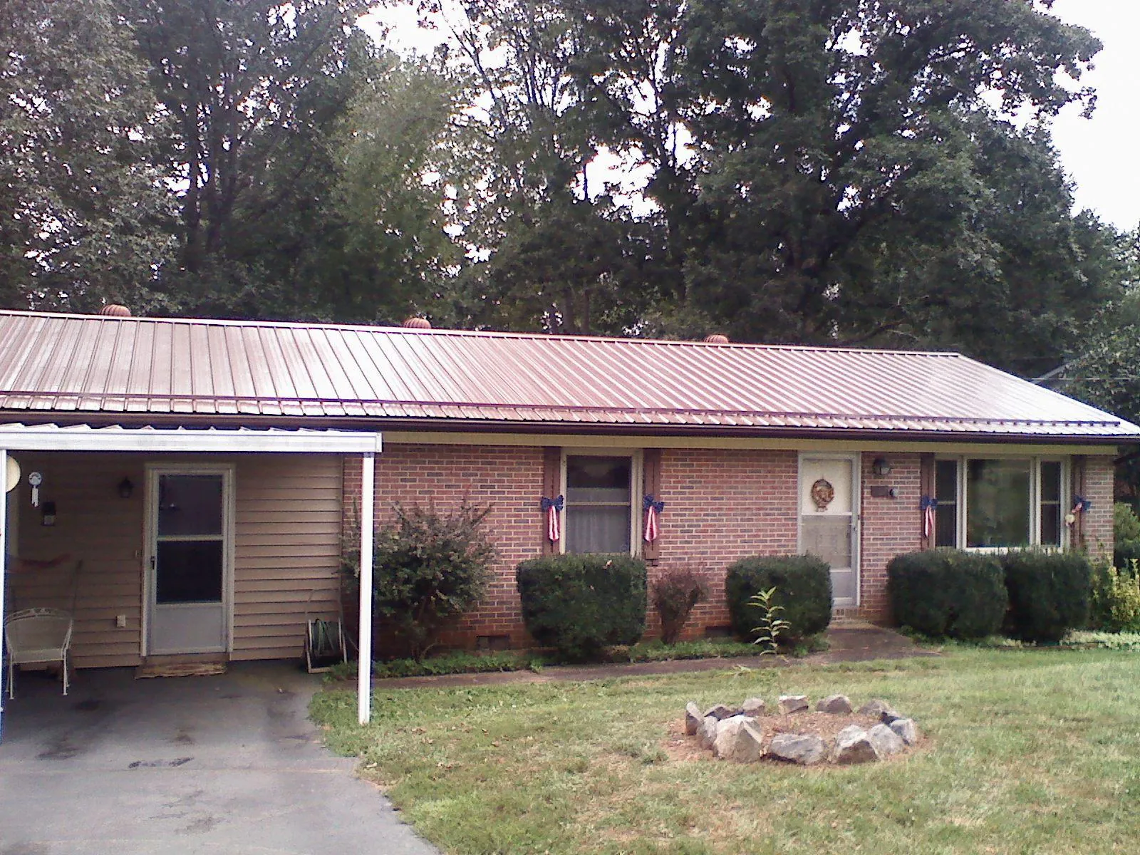 Bronze metal roof and carport on a brick ranch home — Roof Repair work by our crew in Tobaccoville