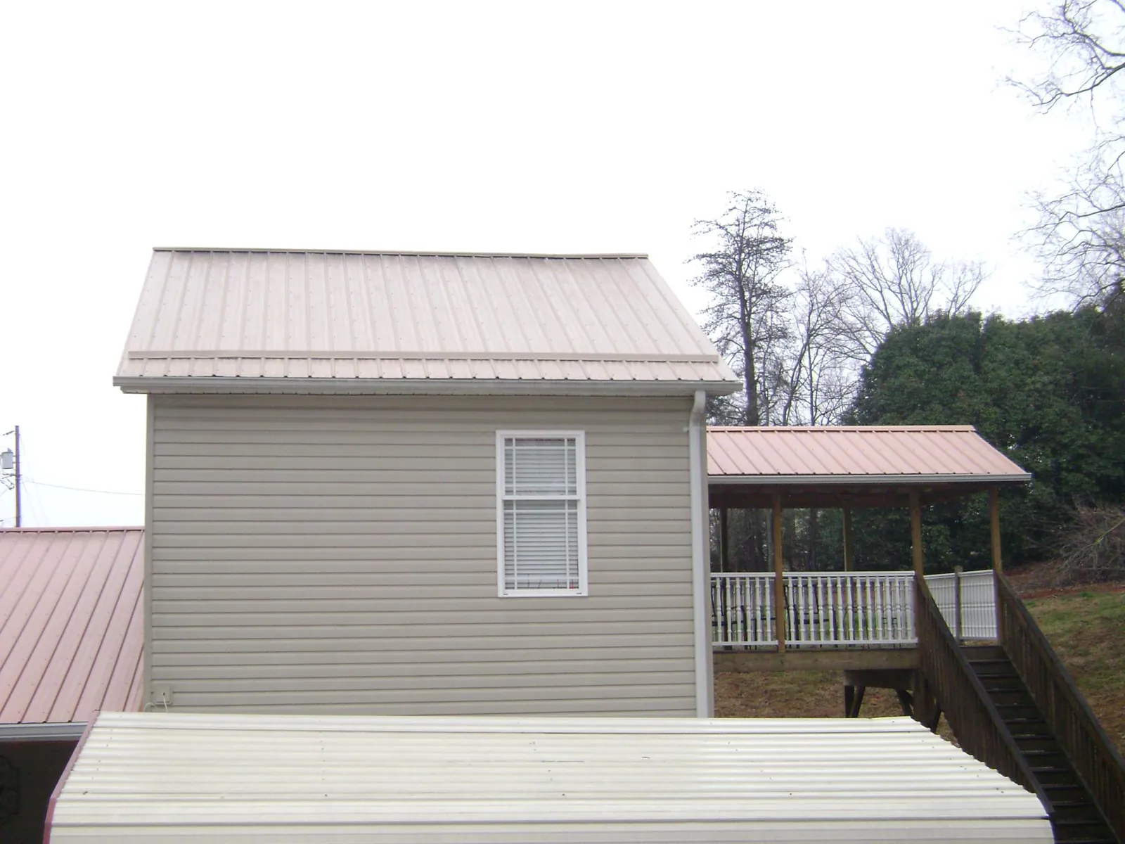 Tan metal roofs on a two story addition and attached porch, from a Roof Replacement job in Tobaccoville