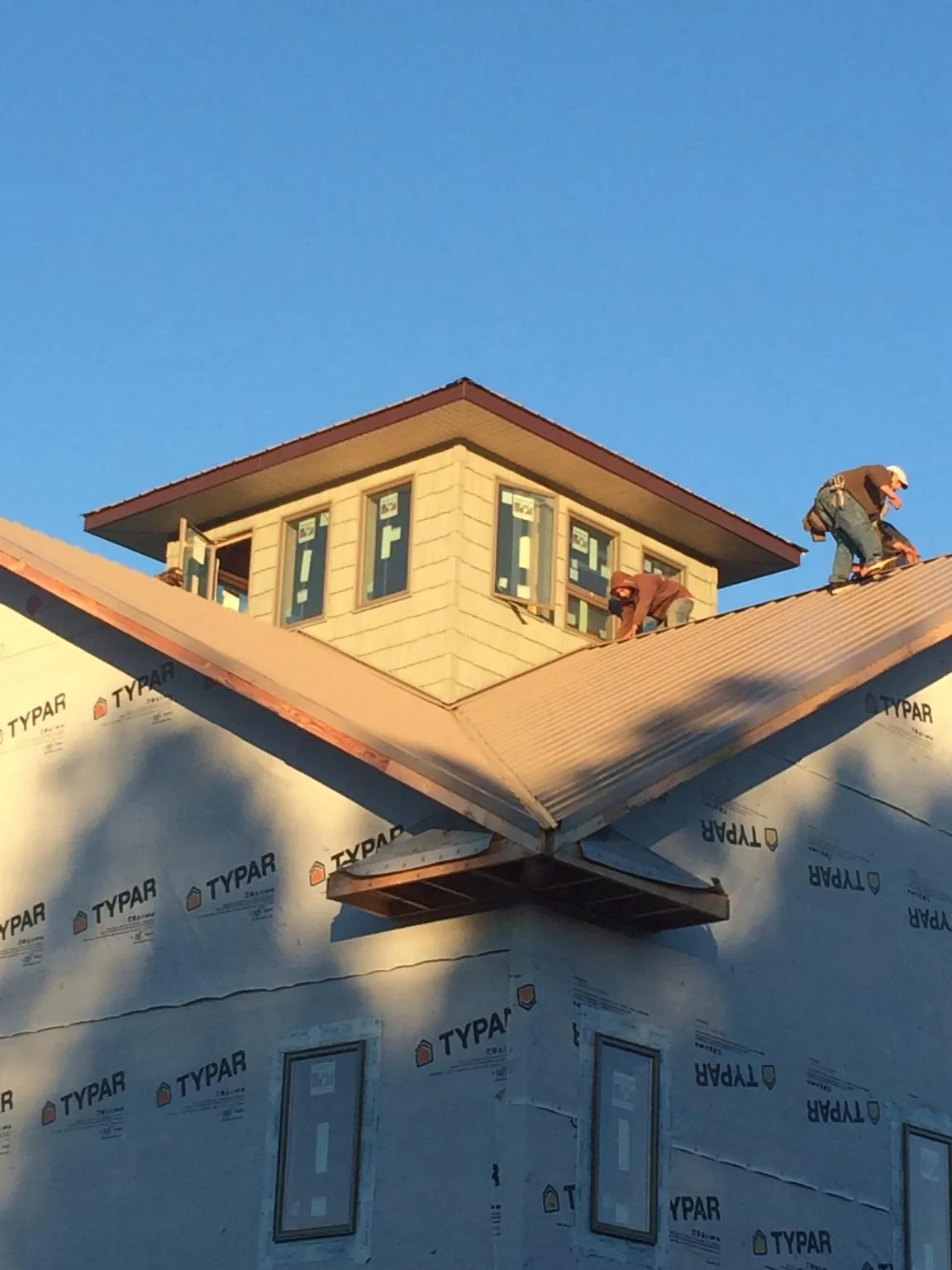 Roofers working around a rooftop cupola on a new metal roof at sunset — Roof Waterproofing in Tobaccoville by Roofing Brothers